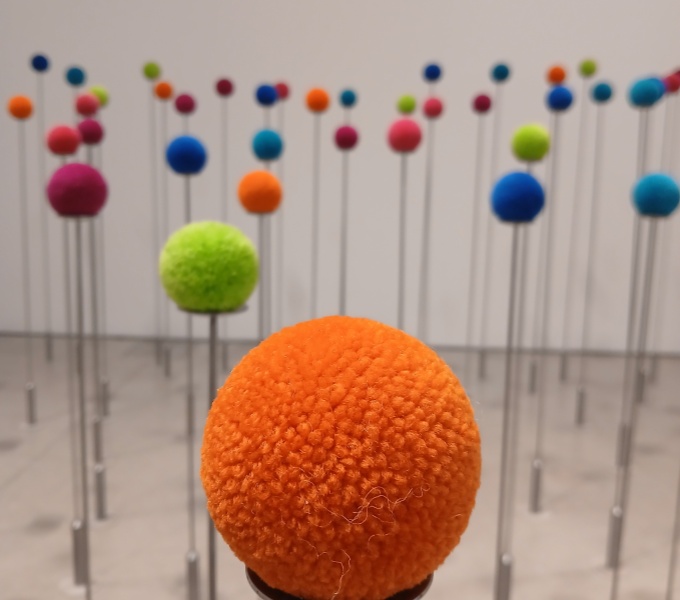 A close up of an orange pom pom with several more behind, just out of focus.