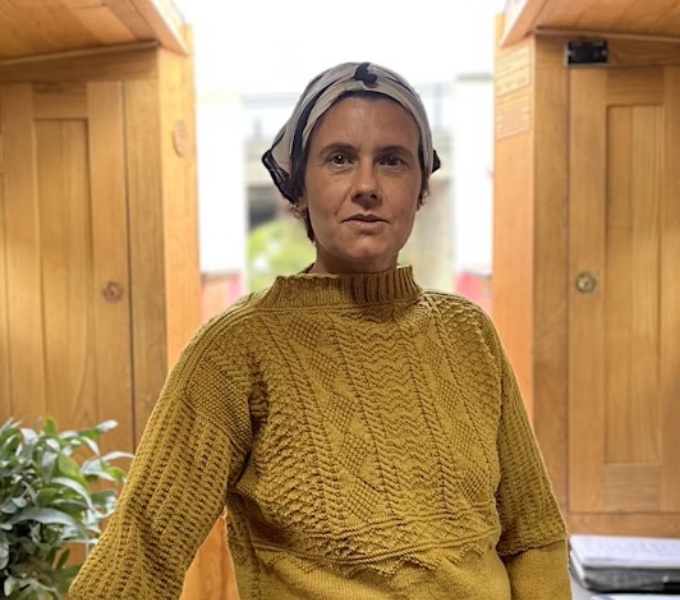 Artist Heather Peak on board the Furor Scribendi, a floating library of short stories, wearing a traditional mustard coloured canal gansey, knitted by the Rishton Library knitters from an original pattern, in the galley of a canal boat.