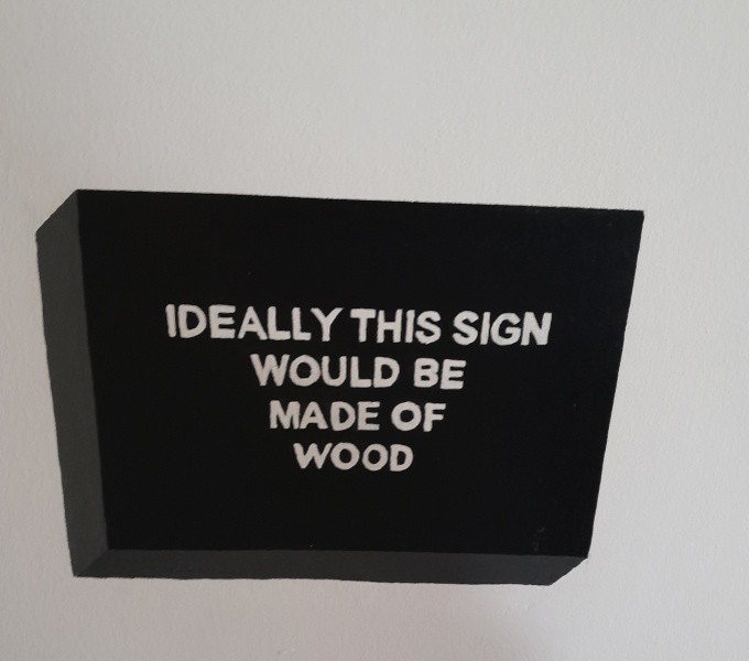 A painted black sign, made to look 3D, with painted white text that reads; Ideally this sign would be made of wood.
